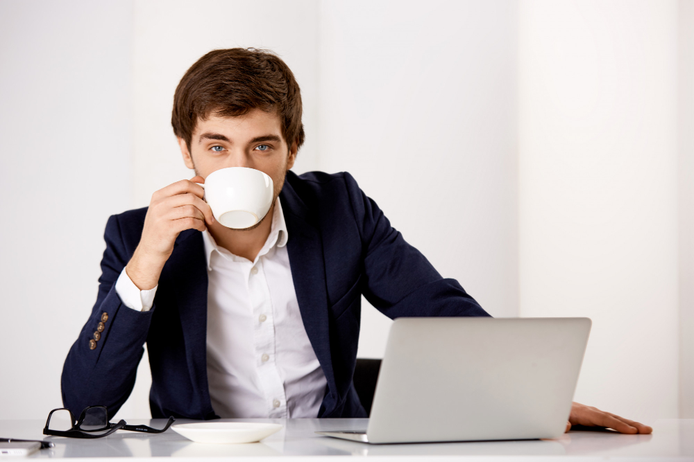 Handsome successful businessman in suit, sit his office with laptop, drinking coffee, ready work productive 
